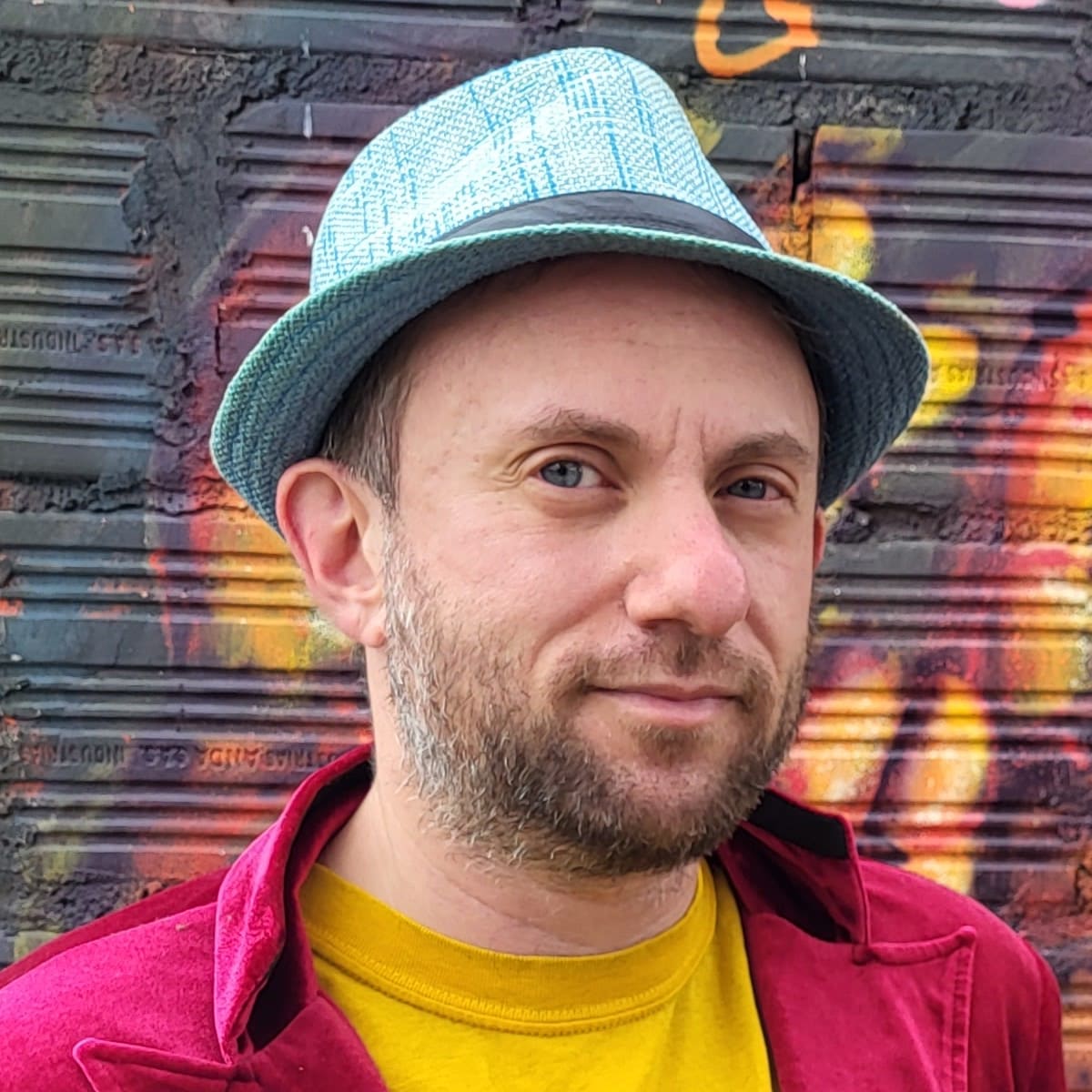 Tucker Lieberman in red jacket, yellow shirt, blue hat. 42-year-old white guy with blue eyes and graying beard.